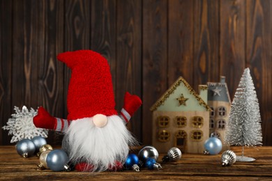 Photo of Cute Christmas gnome and festive decor on wooden table. Space for text