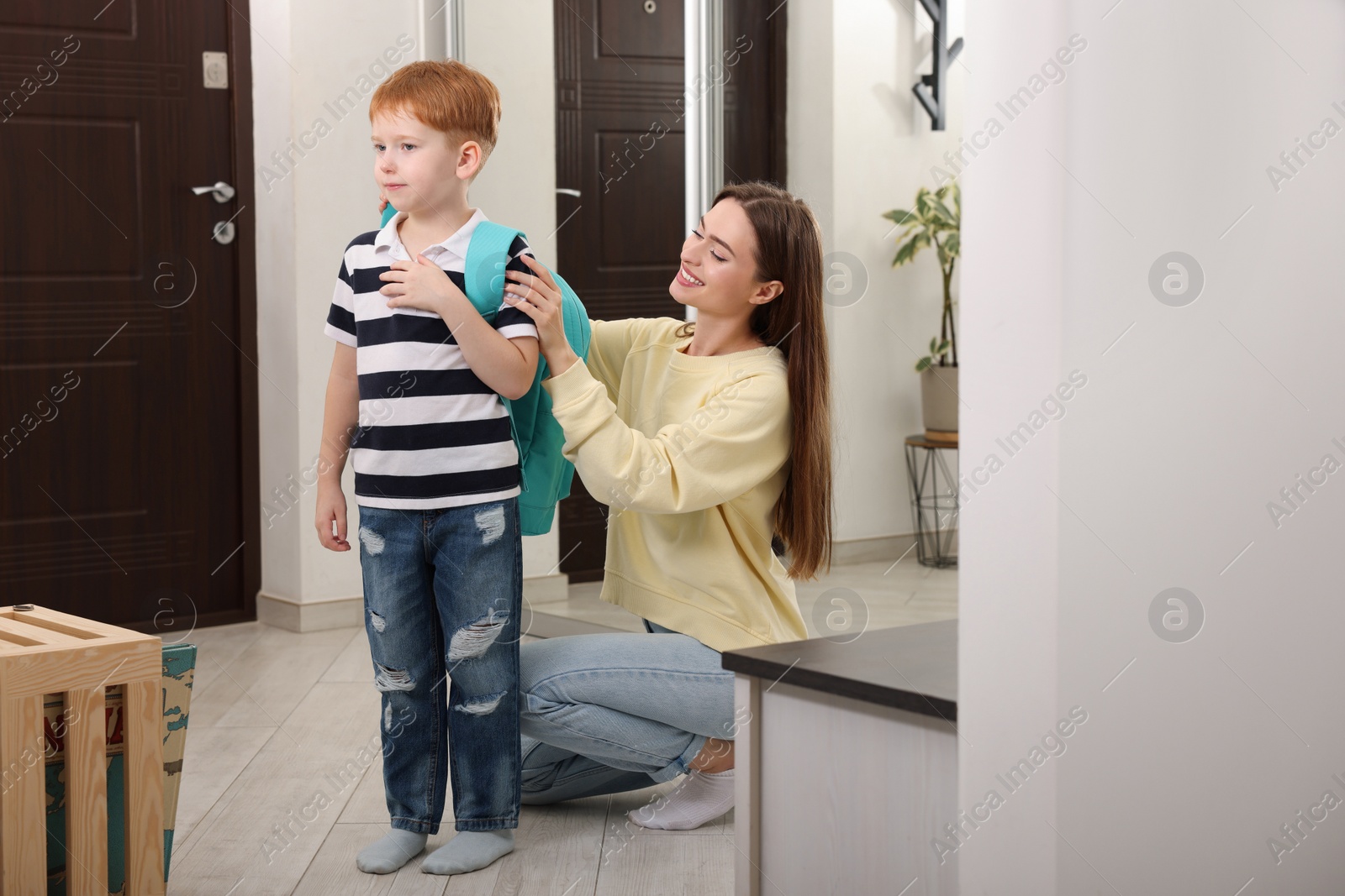 Photo of Young mom preparing her son for school at home