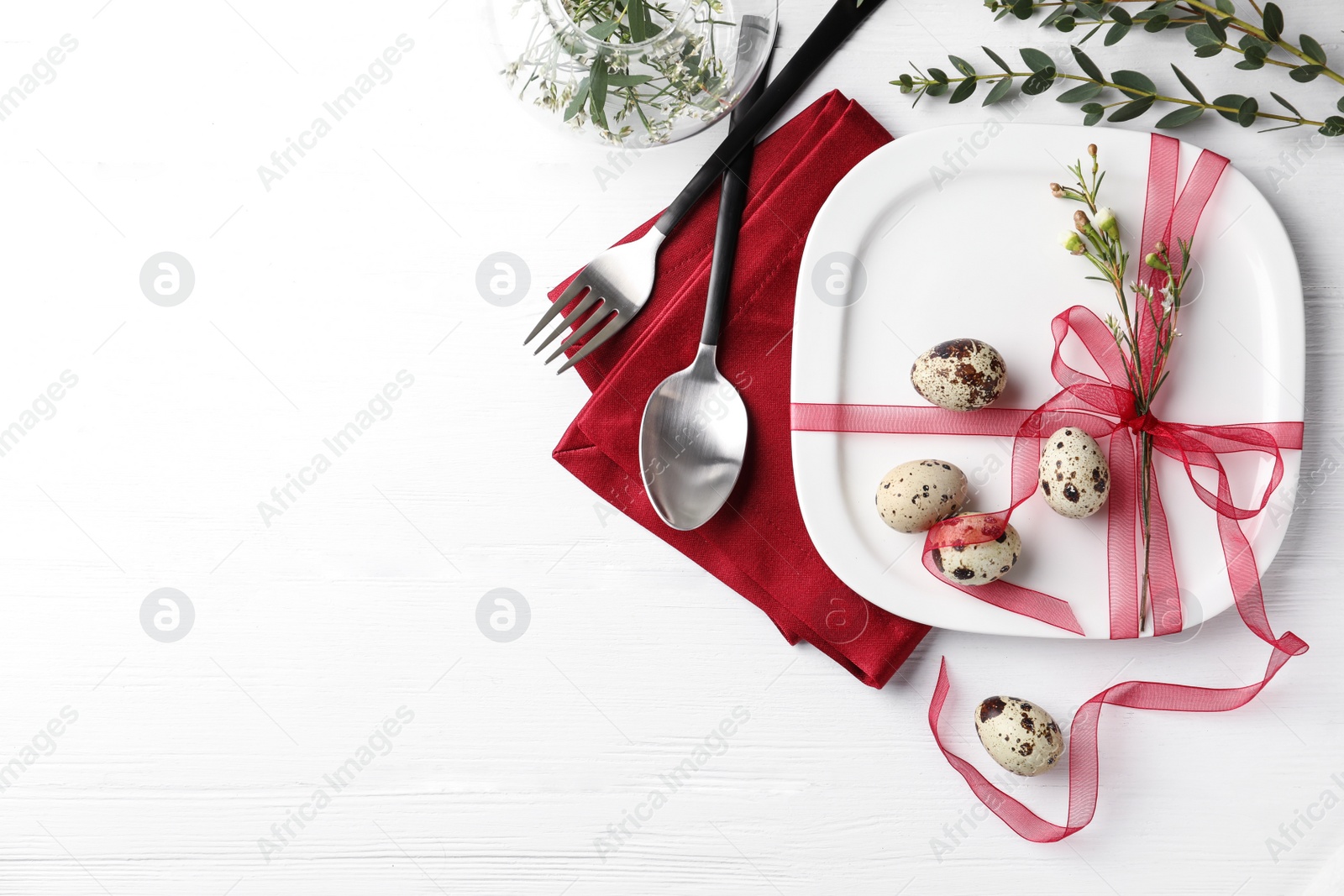 Photo of Festive Easter table setting with ribbon and quail eggs on white wooden background, flat lay. Space for text