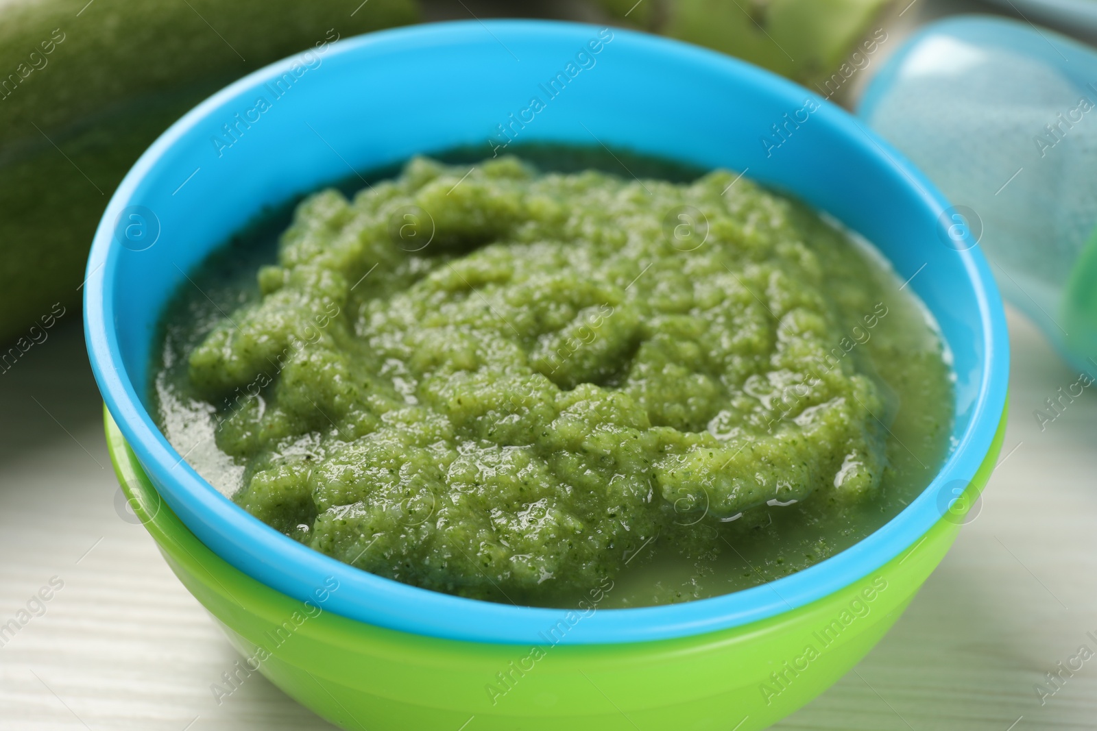Photo of Healthy baby food. Bowl with tasty broccoli puree on white wooden table, closeup