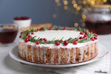 Traditional Christmas cake decorated with rosemary and cranberries on table, closeup