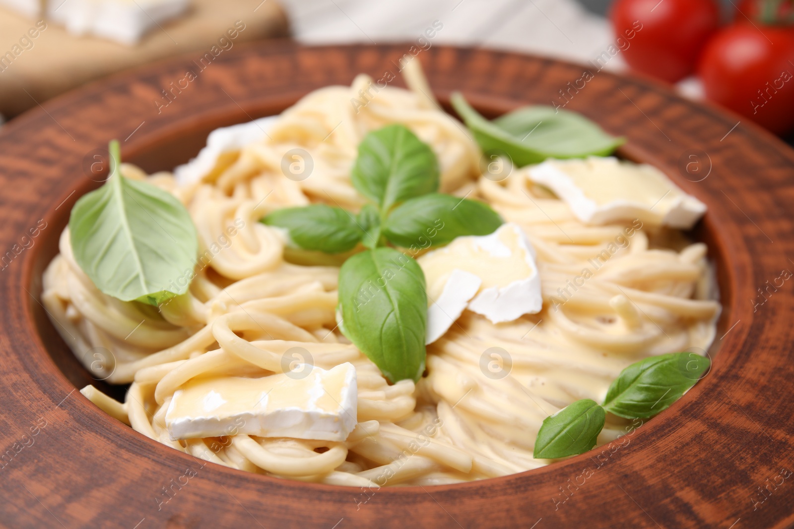 Photo of Delicious pasta with brie cheese and basil leaves in plate, closeup