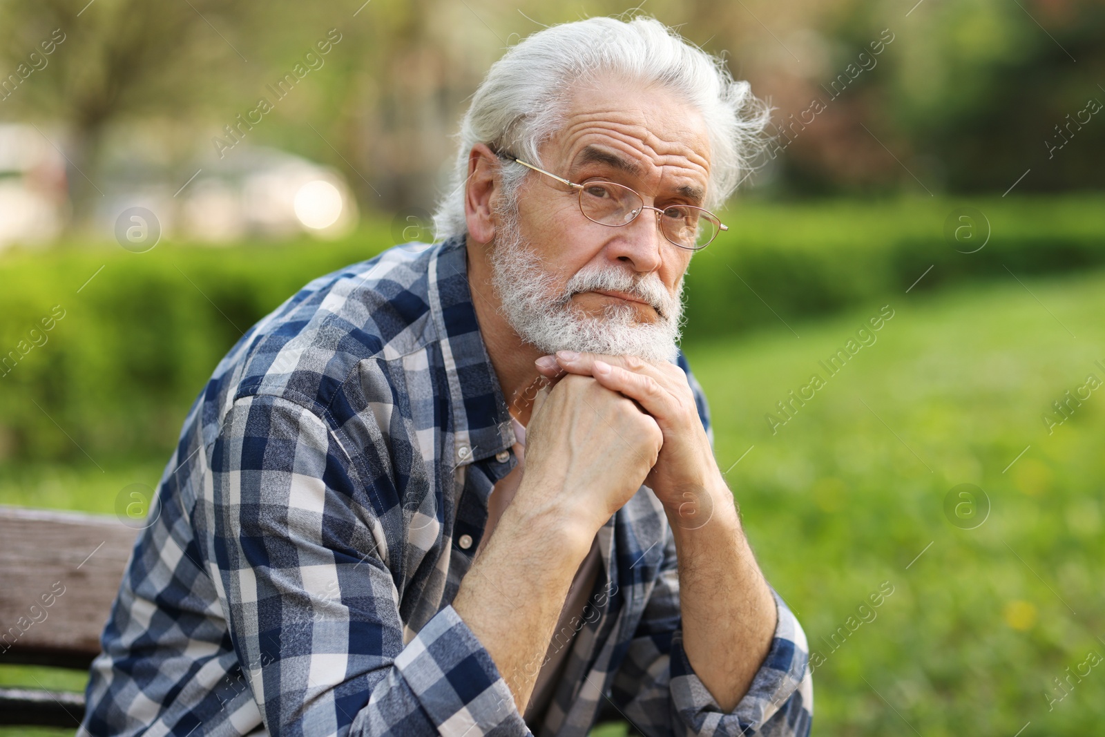 Photo of Portrait of happy grandpa with glasses on bench in park