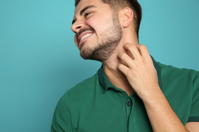 Young man scratching neck on color background. Annoying itch