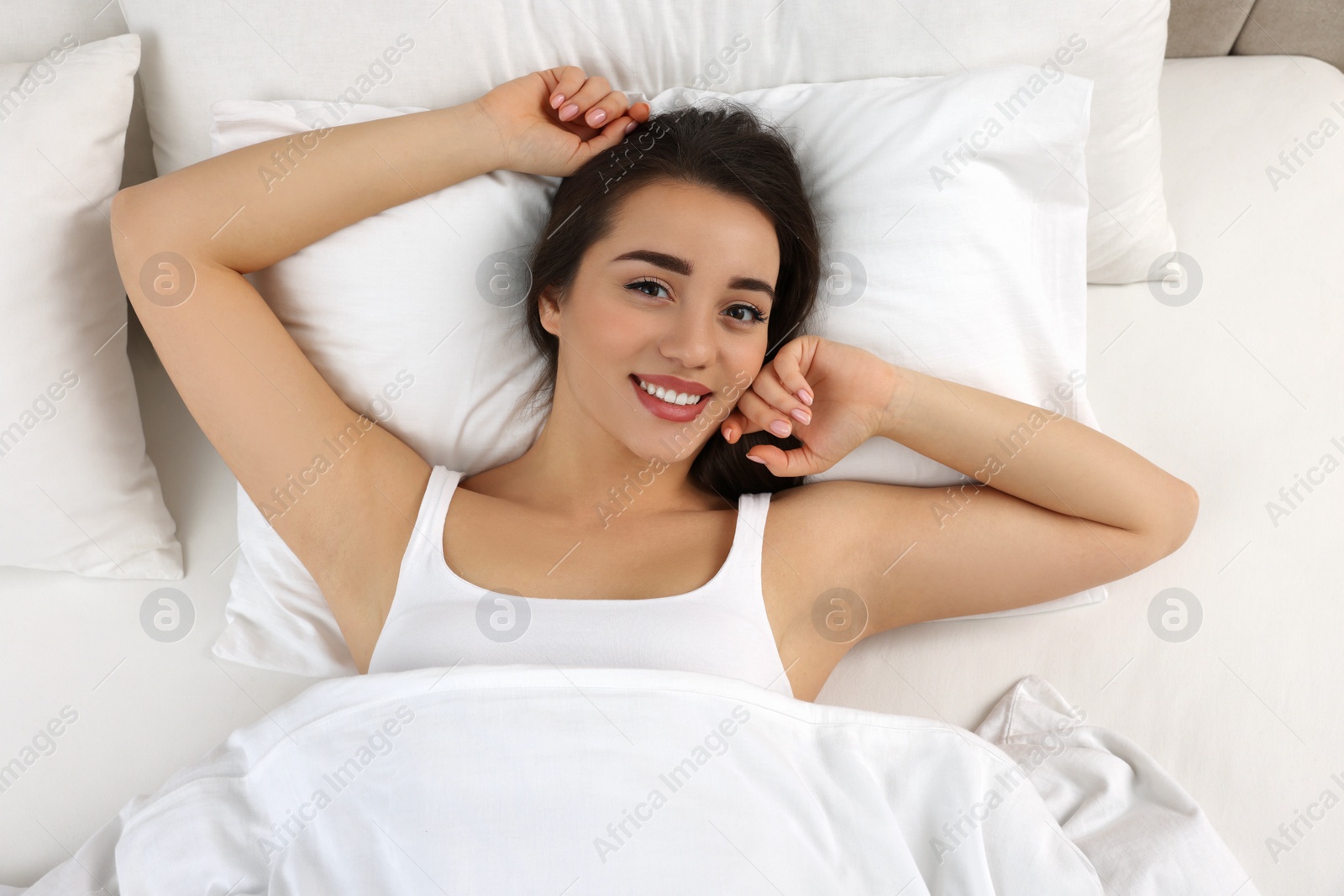 Photo of Beautiful young woman lying in bed, top view
