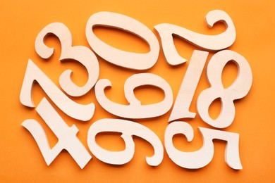 Photo of Wooden numbers on orange background, flat lay