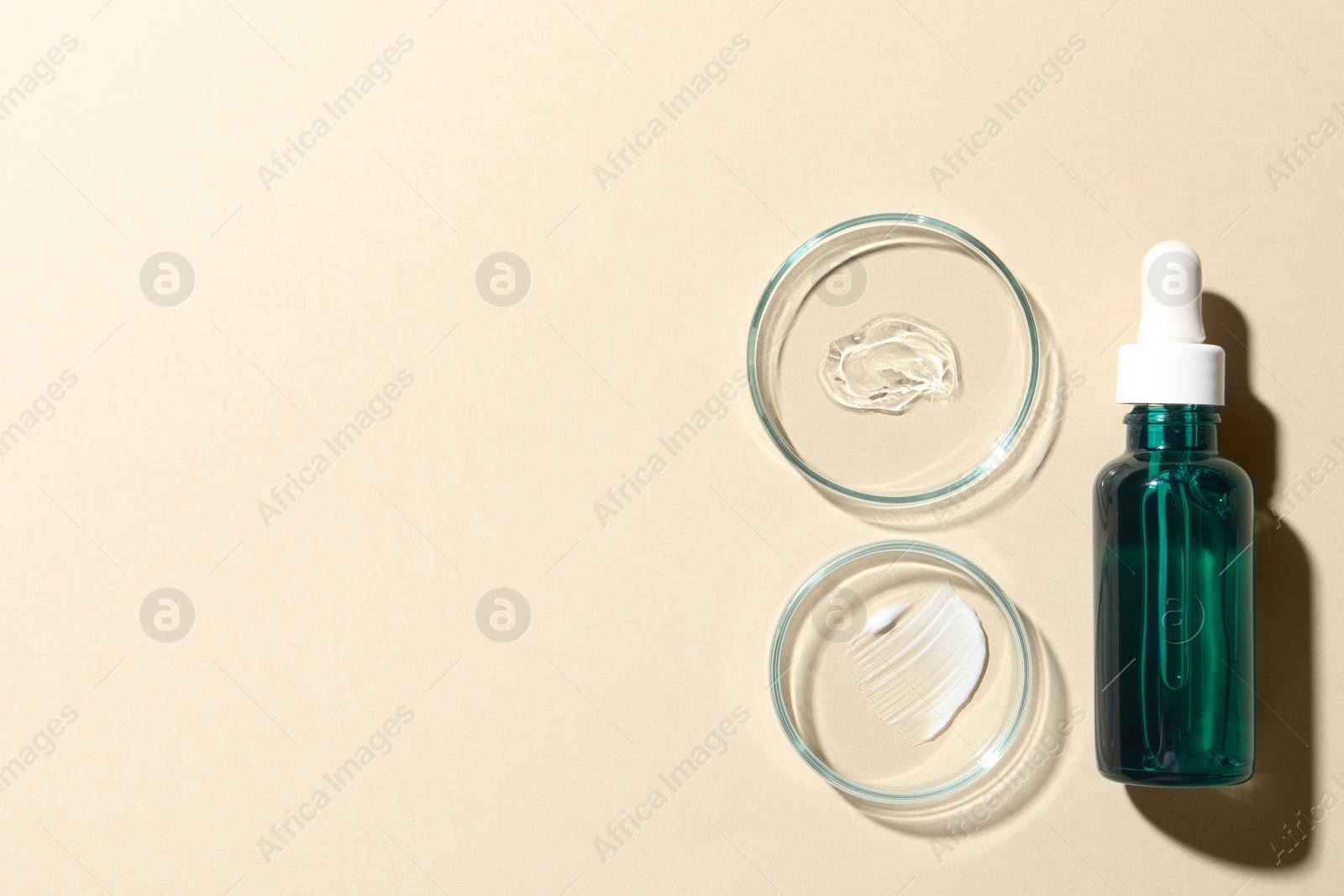 Photo of Bottle of cosmetic serum and petri dishes with samples on beige background, flat lay. Space for text