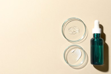 Bottle of cosmetic serum and petri dishes with samples on beige background, flat lay. Space for text