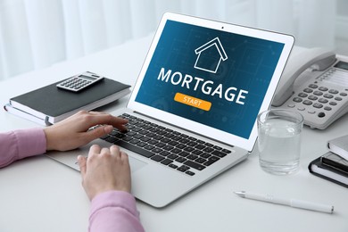 Mortgage concept. Woman using modern laptop at table, closeup