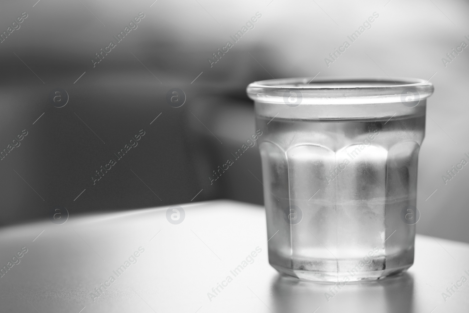 Photo of Glass of pure water on light table against blurred background, space for text