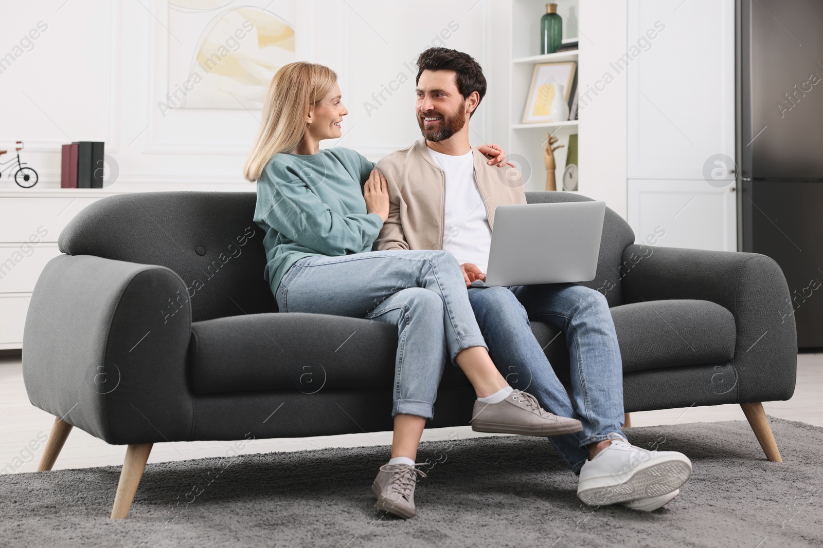 Photo of Happy couple with laptop on sofa at home