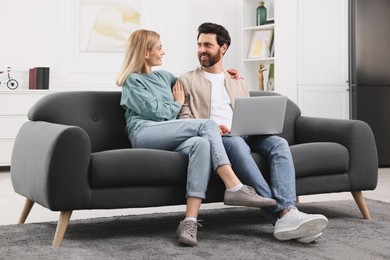 Happy couple with laptop on sofa at home