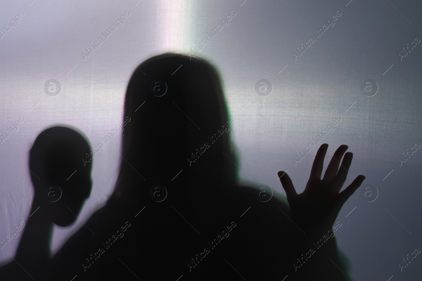 Photo of Silhouette of creepy ghost with skull behind cloth against grey background