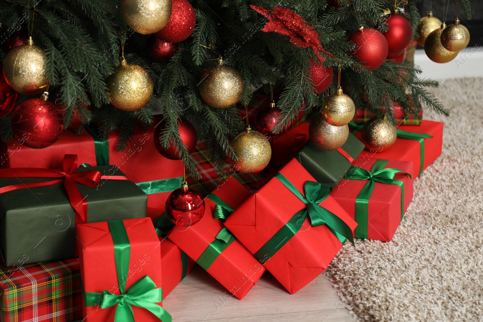 Photo of Many gift boxes under decorated Christmas tree in room