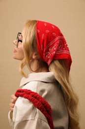 Young woman with stylish bandana on beige background