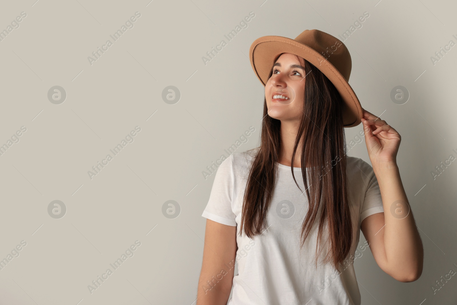 Photo of Smiling young woman in stylish outfit on light grey background. Space for text