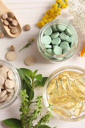 Different pills, flowers and herbs on white wooden table, flat lay. Dietary supplements