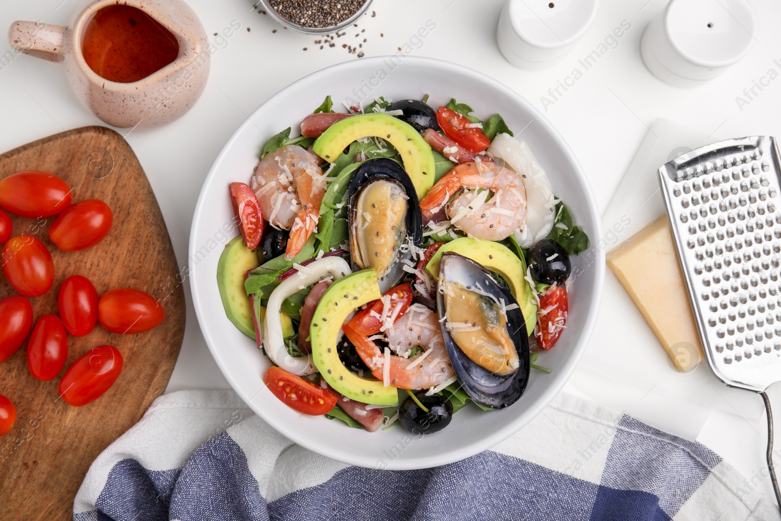 Photo of Bowl of delicious salad with seafood on white table, flat lay