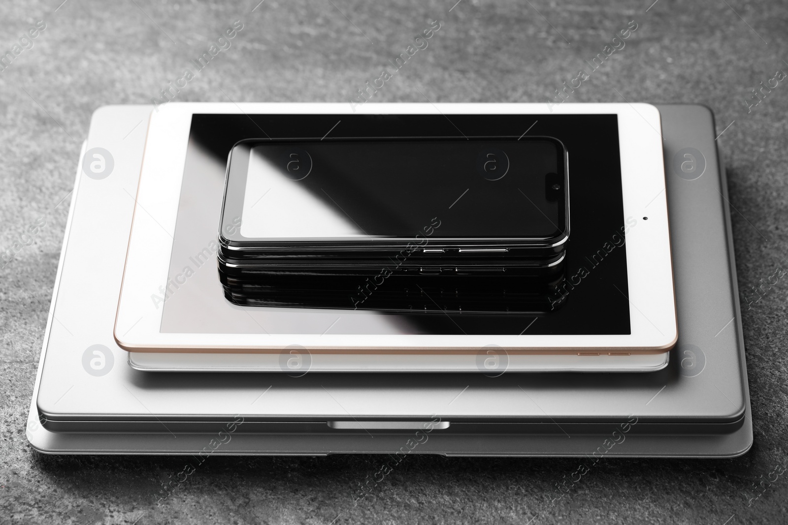 Photo of Stack of electronic devices on grey table, closeup