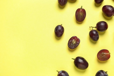 Flat lay composition with fresh ripe juicy grapes on yellow background, space for text