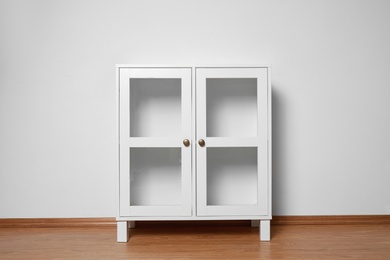 Photo of Empty wooden cabinet near white wall. Stylish home furniture