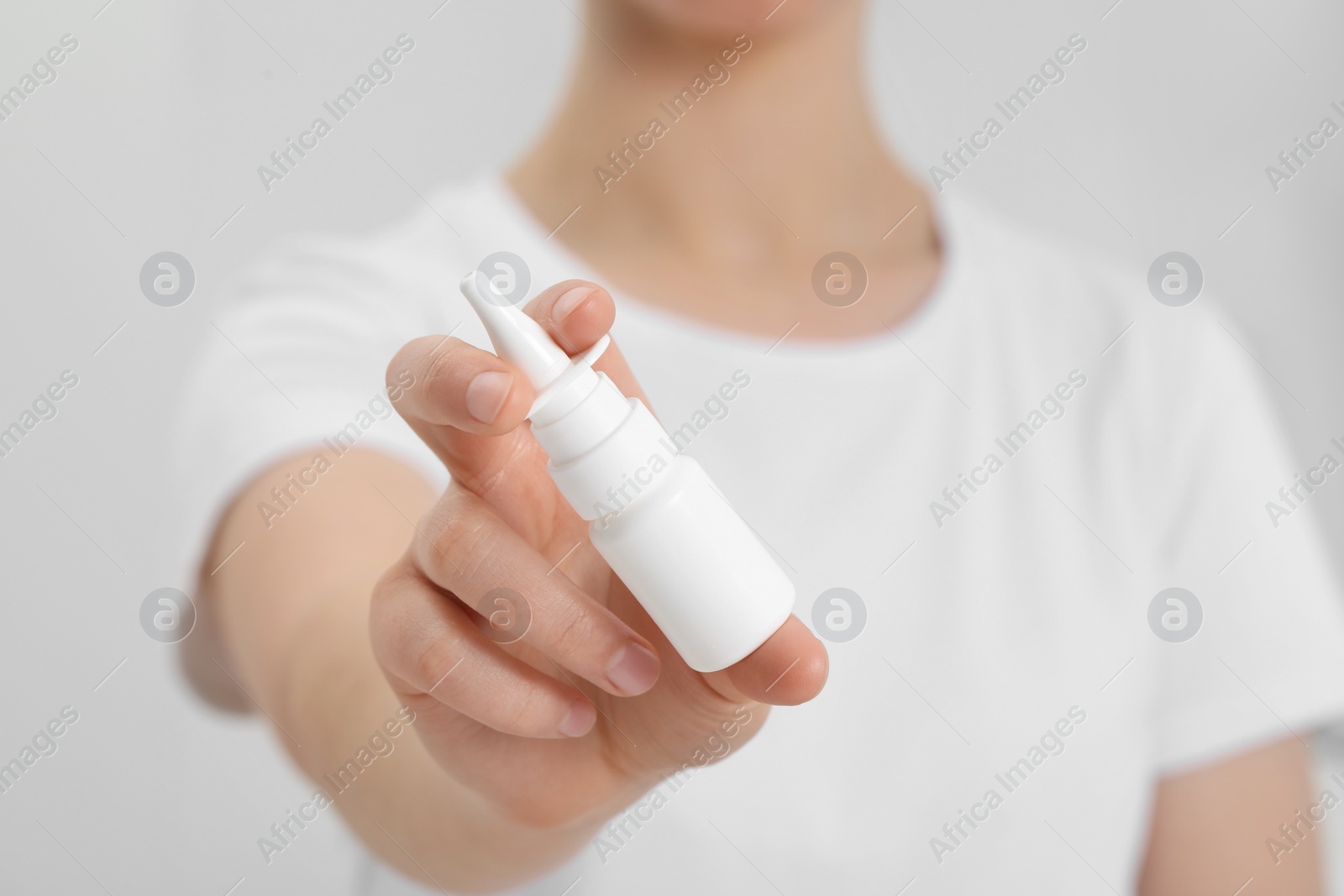 Photo of Woman holding nasal spray indoors, closeup view