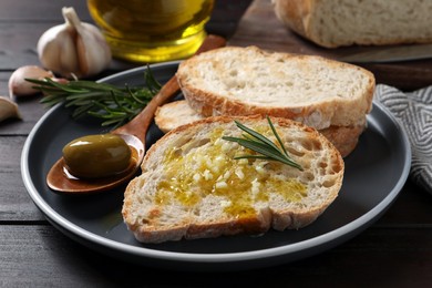 Photo of Tasty bruschettas with oil and rosemary on plate, closeup