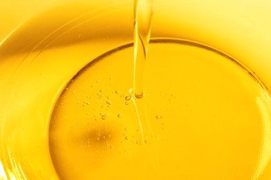 Photo of Pouring cooking oil into glass bowl, closeup