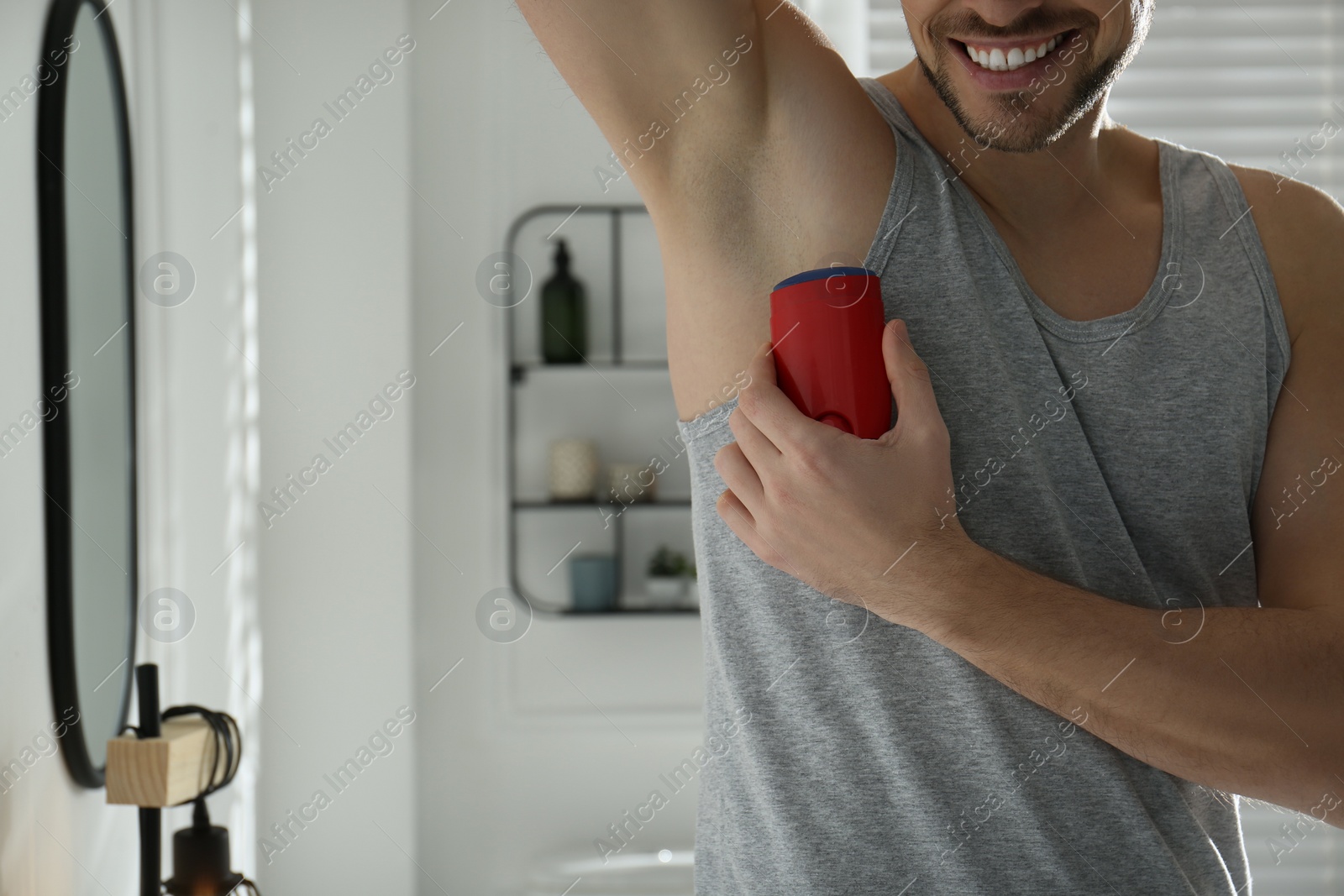 Photo of Man applying deodorant in bathroom, closeup. Space for text