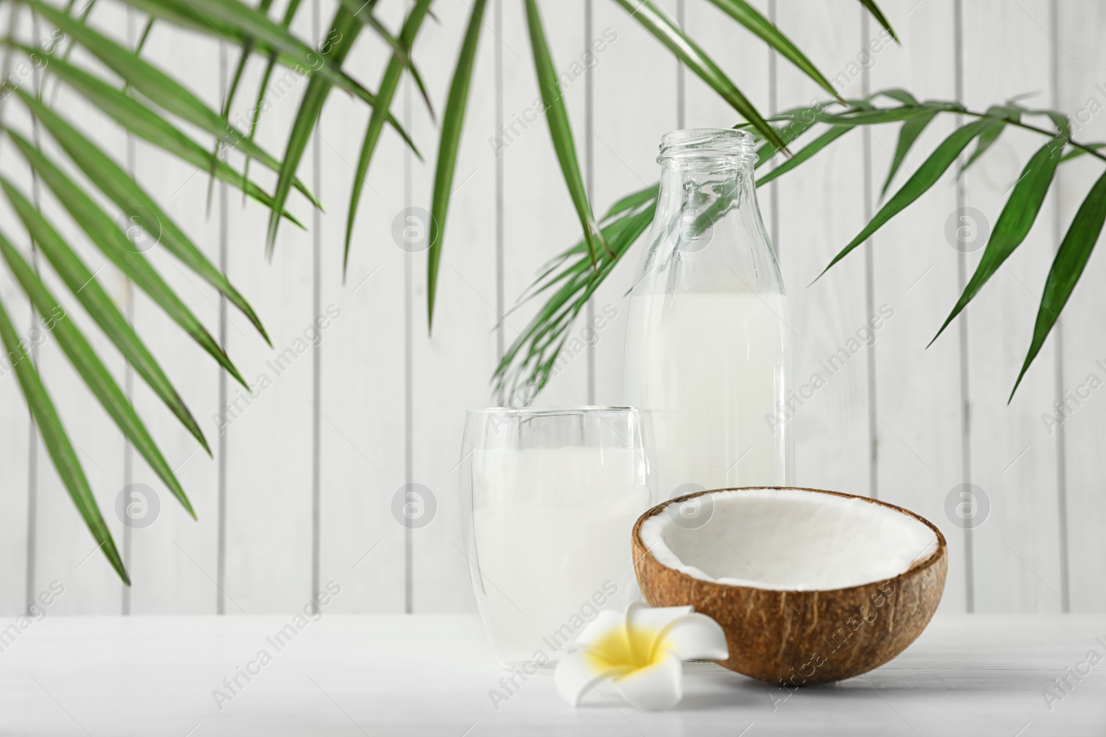 Photo of Composition with bottle and glass of coconut water on white wooden table