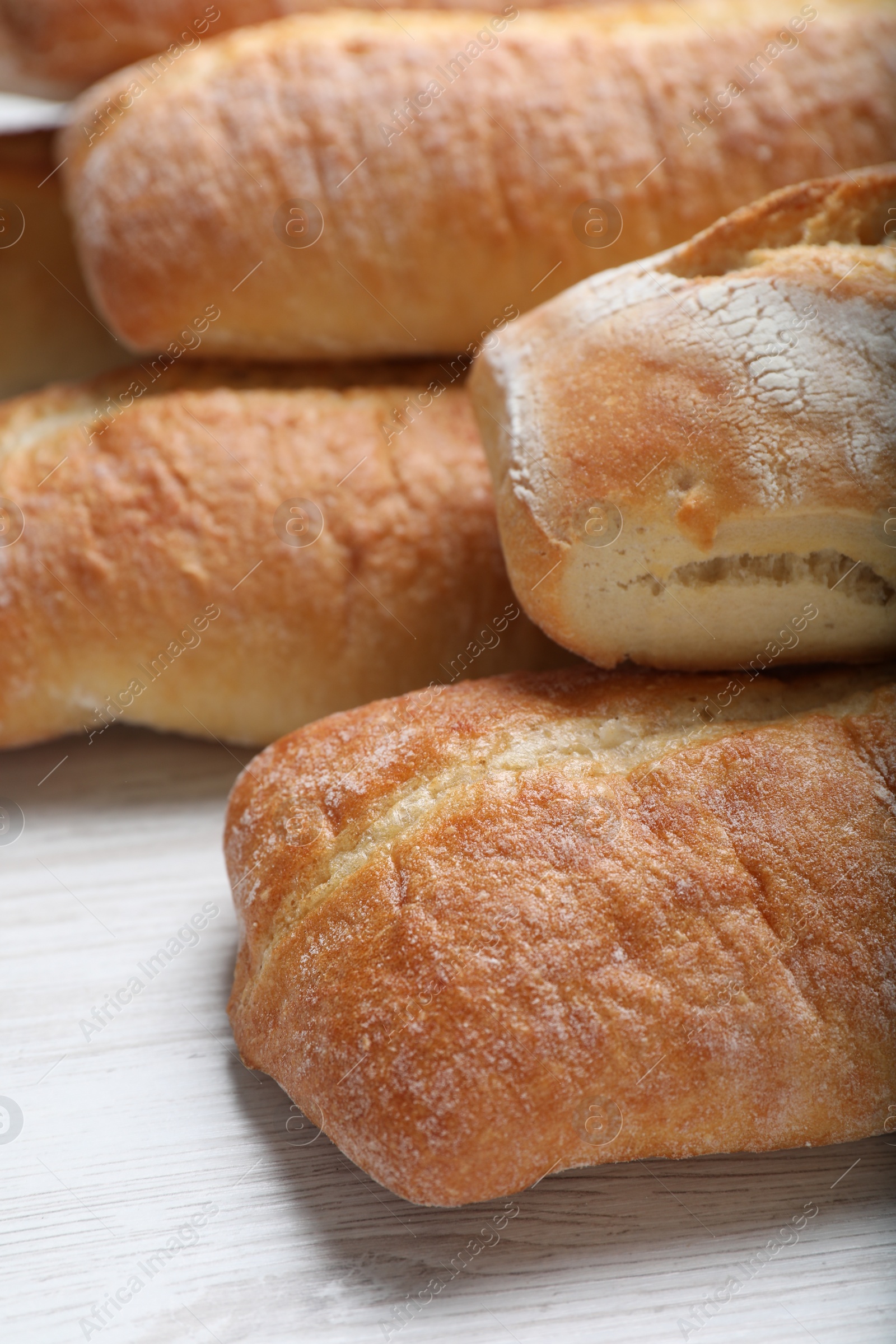 Photo of Tasty baguettes on white wooden table, closeup