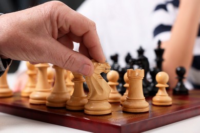 Photo of Senior man playing chess with his grandson indoors, closeup