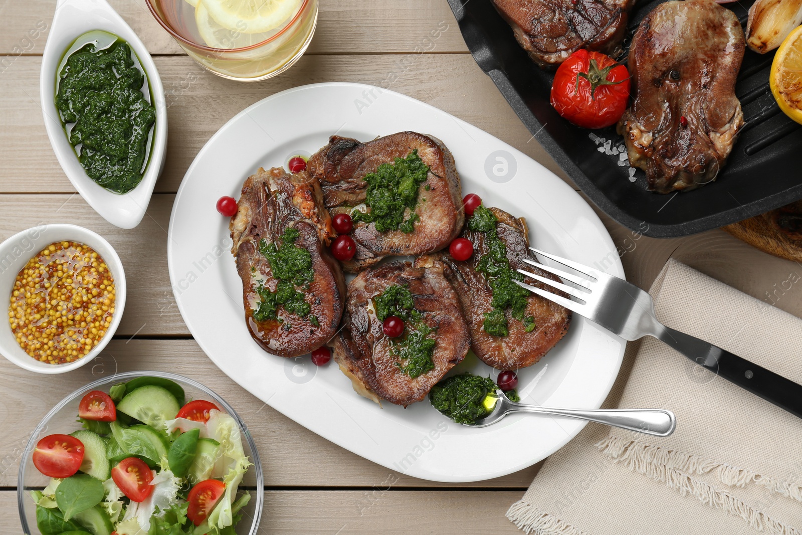 Photo of Tasty beef tongue pieces, salsa verde, berries, mustard and salad on beige wooden table, flat lay