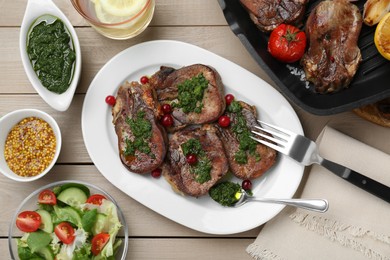 Tasty beef tongue pieces, salsa verde, berries, mustard and salad on beige wooden table, flat lay