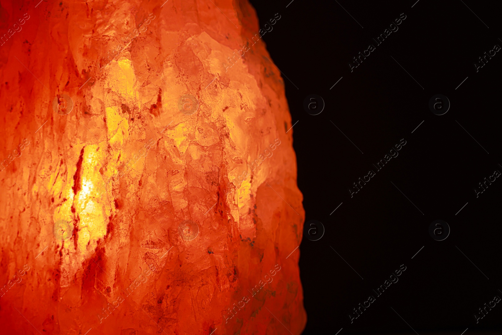 Photo of Himalayan salt lamp on dark background, closeup. Space for text