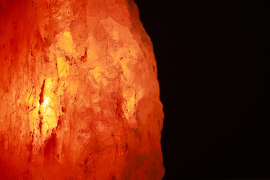 Photo of Himalayan salt lamp on dark background, closeup. Space for text