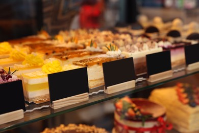 Showcase with different tasty desserts in bakery shop, closeup