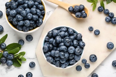 Tasty fresh blueberries on white marble table, flat lay