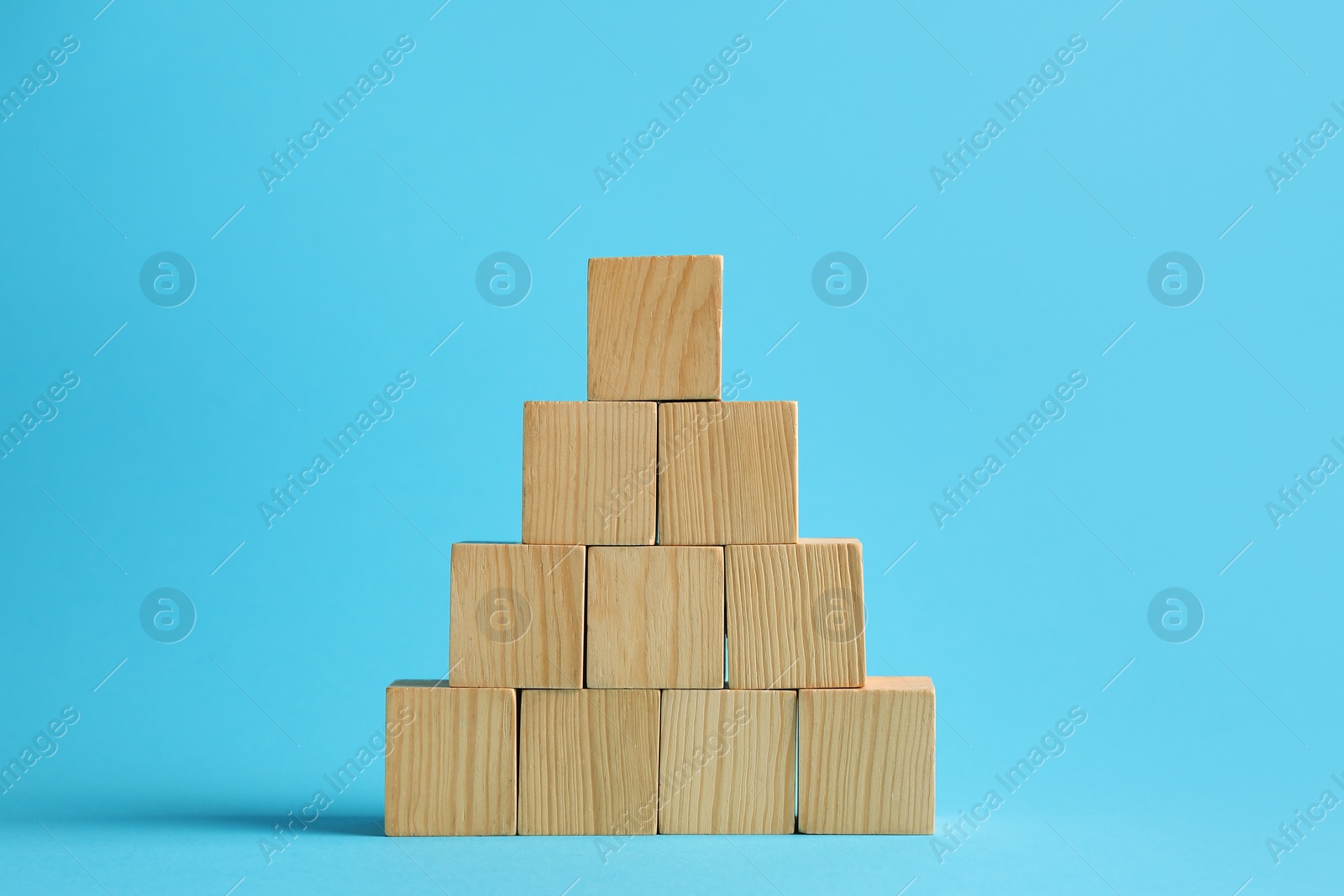 Photo of Pyramid of blank wooden cubes on light blue background