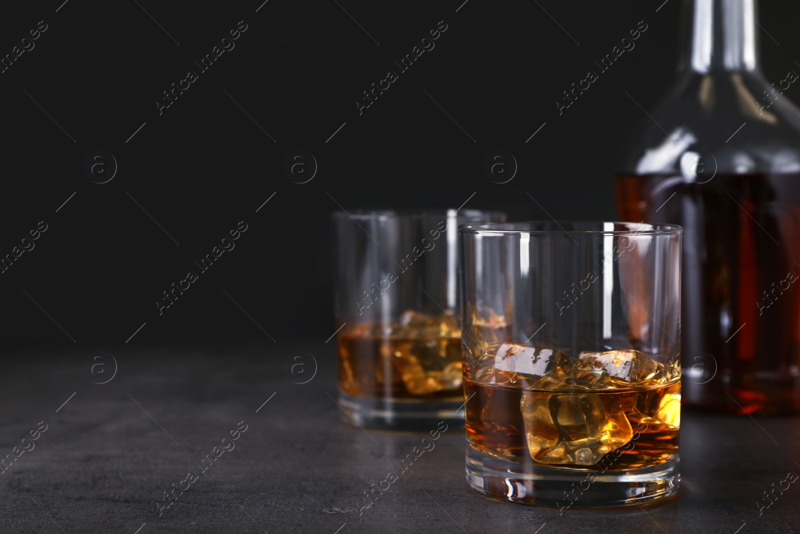 Photo of Golden whiskey in glass with ice cubes on table. Space for text