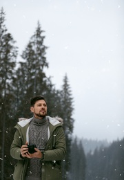 Photo of Man with camera walking near forest on snowy winter day