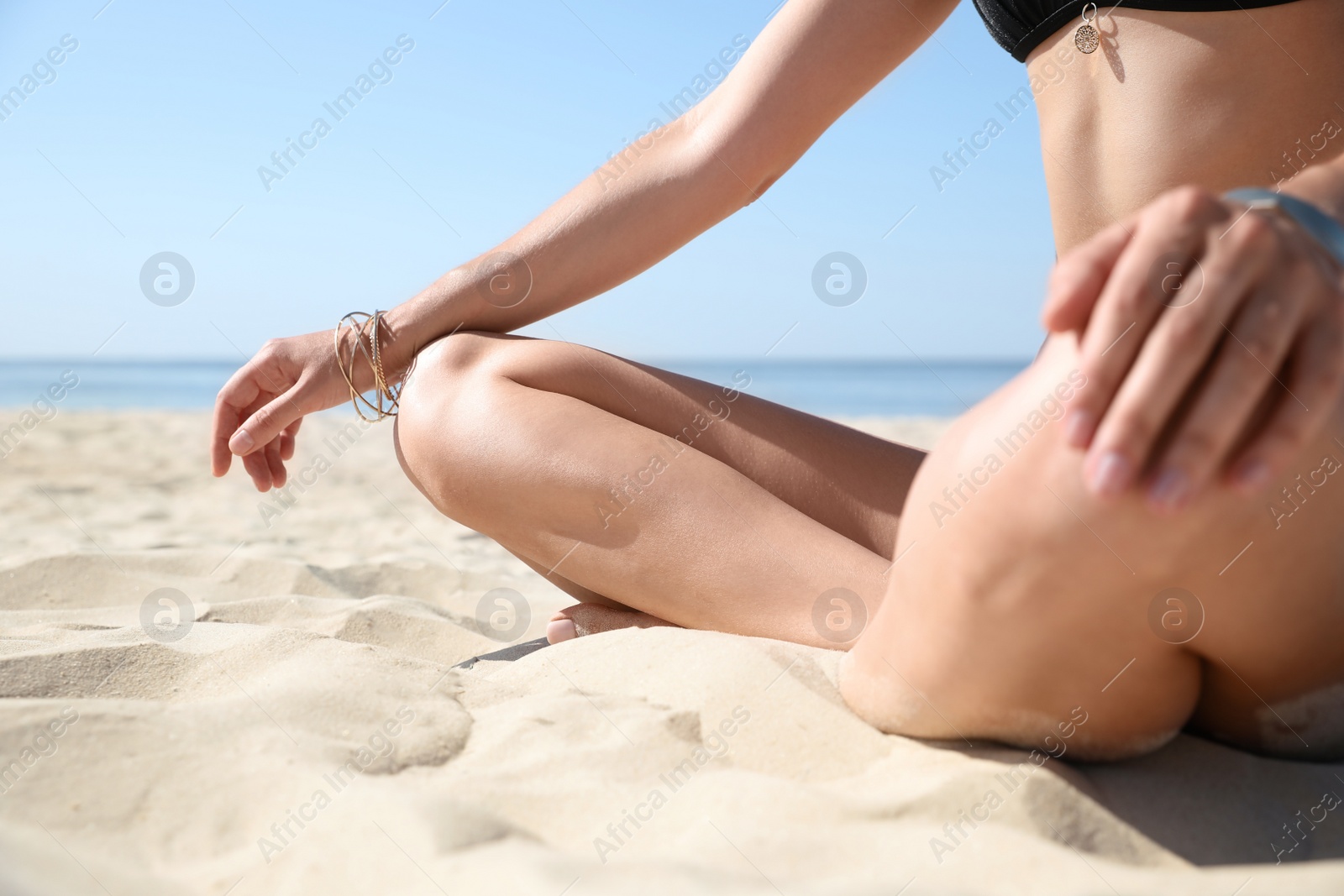 Photo of Young woman with beautiful body on sandy beach, closeup