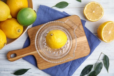 Photo of Glass squeezer, fresh lemons and lime on white wooden table, flat lay