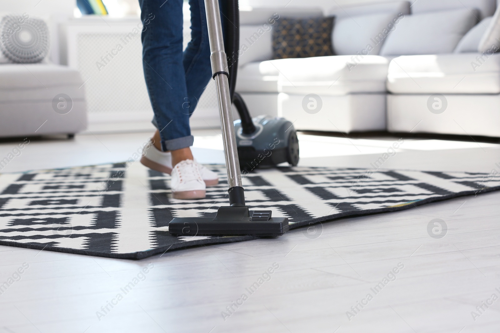 Photo of Woman cleaning carpet with vacuum cleaner, closeup