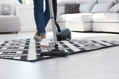 Woman cleaning carpet with vacuum cleaner, closeup