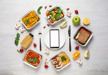 Photo of Flat lay composition with lunchboxes and smartphone on white wooden table, mockup for design. Healthy food delivery