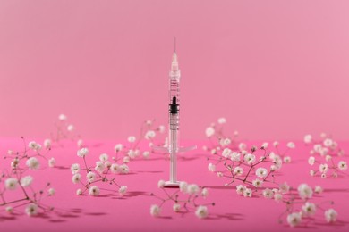 Photo of Cosmetology. Medical syringe and gypsophila flowers on pink background