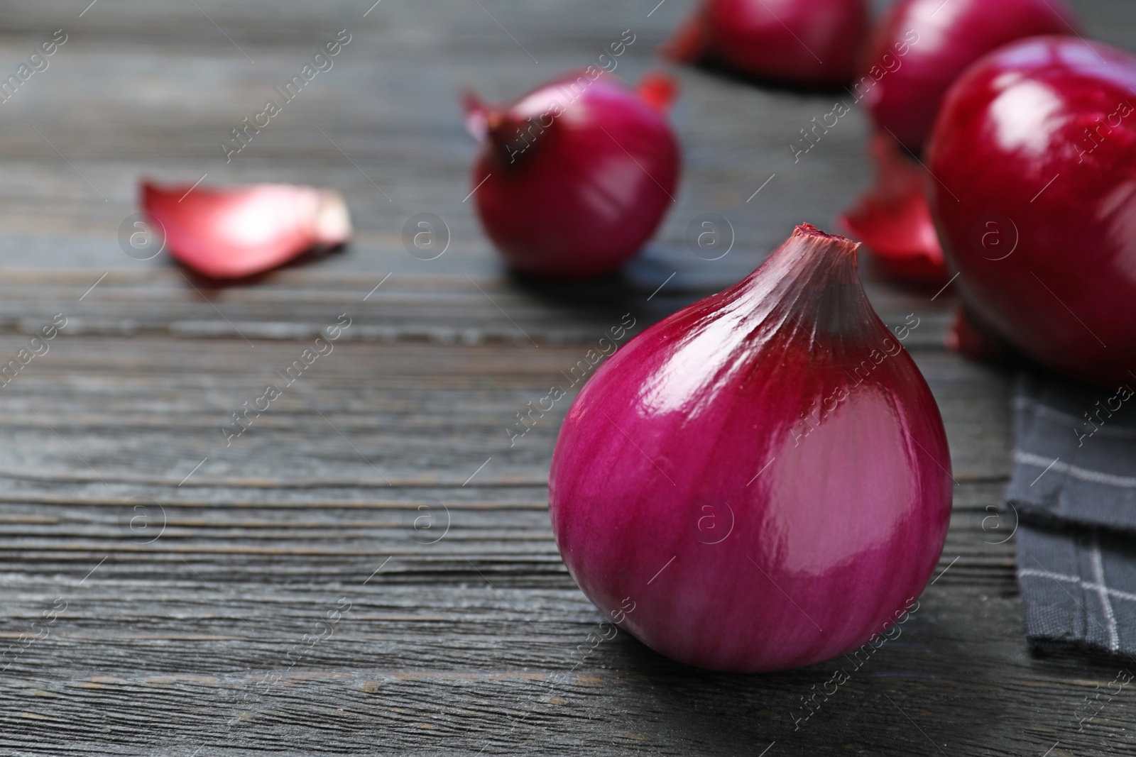 Photo of Fresh whole red onion bulb on dark wooden table, closeup. Space for text