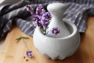 Photo of Mortar with fresh lavender flowers and pestle on wooden table, closeup