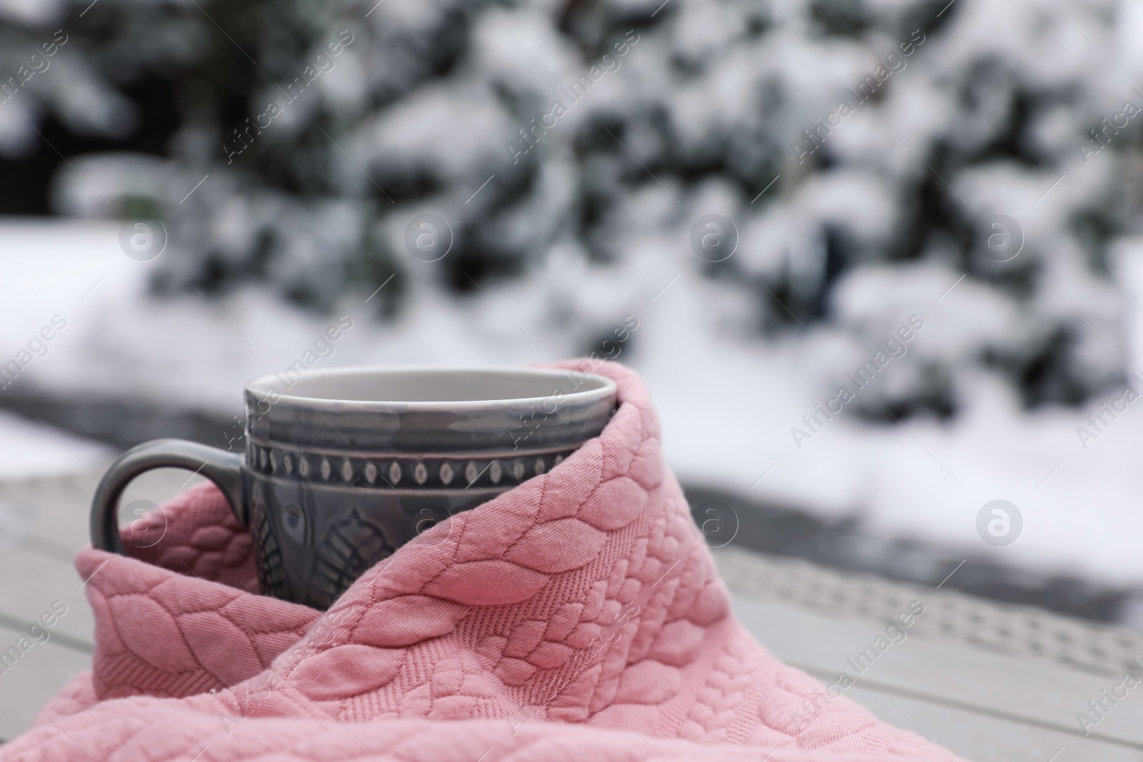 Photo of Winter morning. Cup with hot drink wrapped in pink sweater outdoors, closeup. Space for text